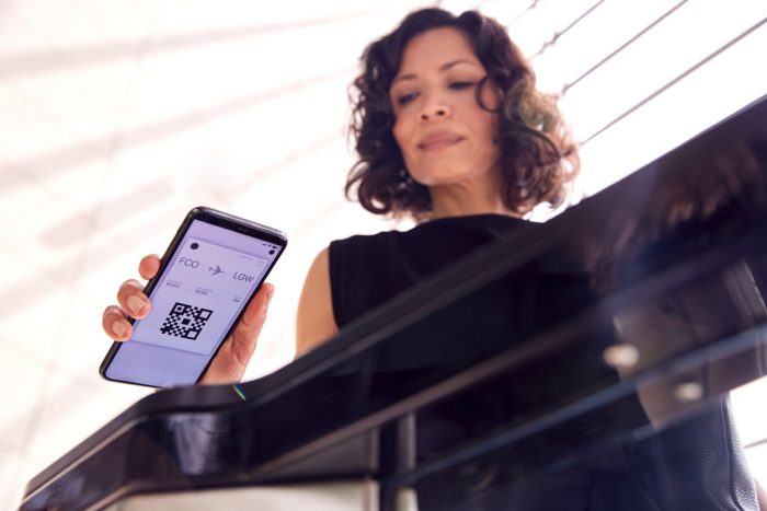 Businesswoman In Airport Departure Lounge Scanning Digital Boarding Pass On Smart Phone Airports Passenger Touchpoint Tracker